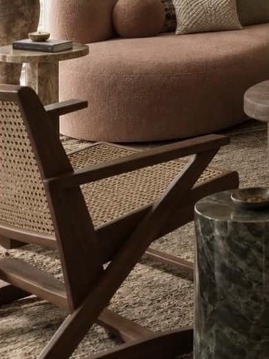 Cane and dark timber lounge chair beside a green marble drum side table.